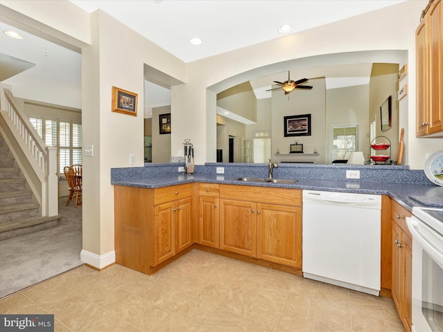 kitchen with stove, sink, white dishwasher, ceiling fan, and light carpet