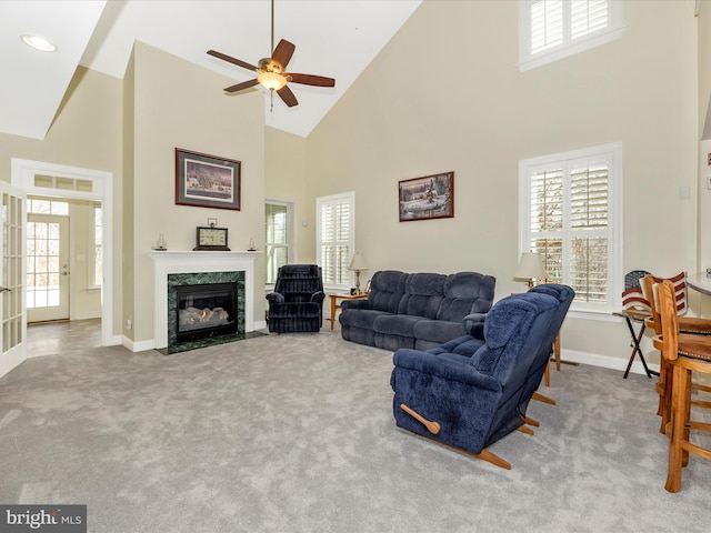 carpeted living room with high vaulted ceiling, a wealth of natural light, and a high end fireplace