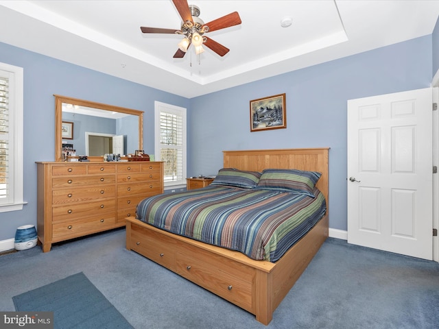 bedroom featuring dark colored carpet, ceiling fan, and a raised ceiling