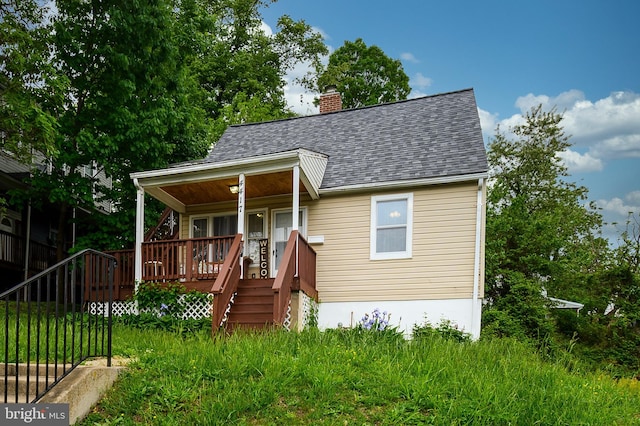 bungalow-style house featuring roof with shingles, a chimney, and a porch