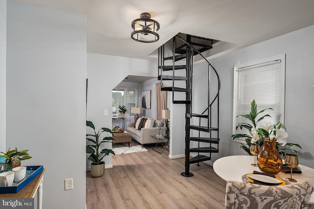 hall with stairway, wood finished floors, baseboards, and arched walkways