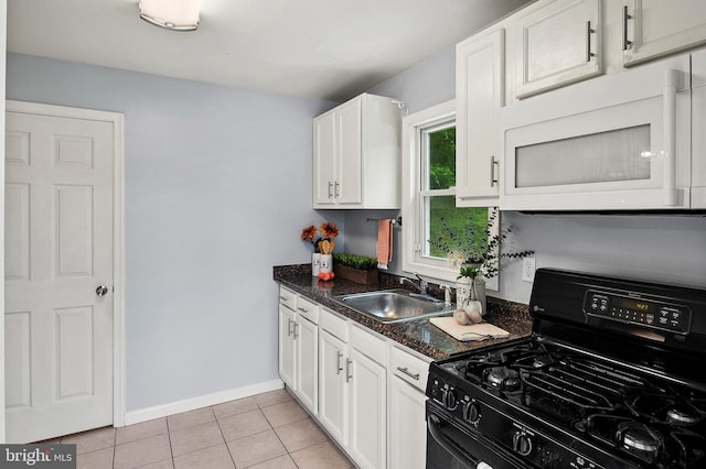 kitchen with black range with gas stovetop, white microwave, a sink, white cabinetry, and light tile patterned floors