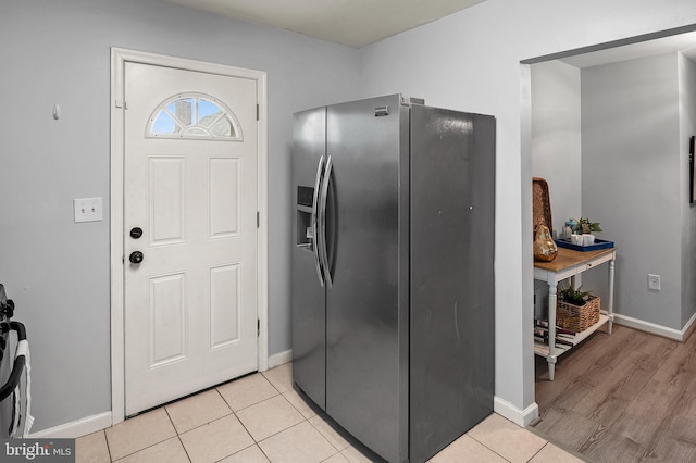 kitchen featuring stainless steel fridge, baseboards, and light tile patterned floors