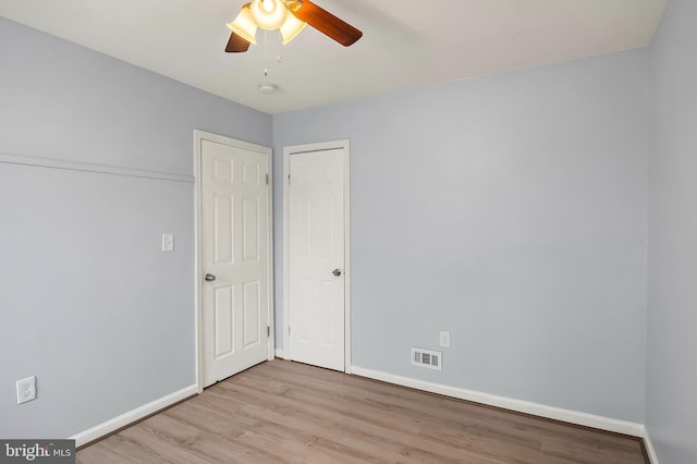 empty room featuring wood finished floors, baseboards, ceiling fan, and a smoke detector