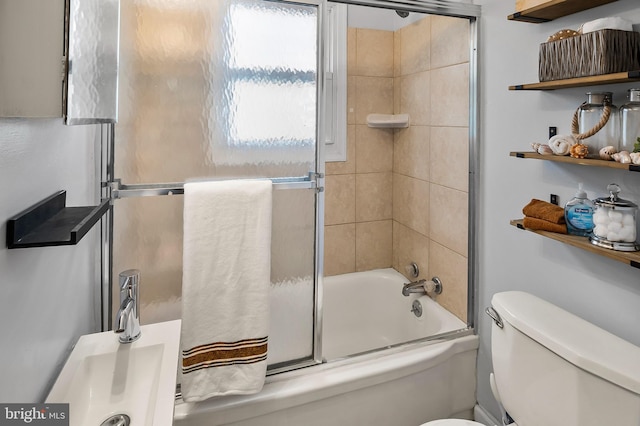 bathroom featuring toilet and bath / shower combo with glass door