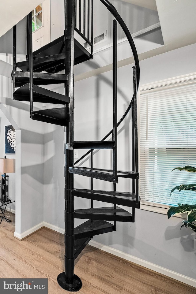 staircase featuring wood finished floors and baseboards