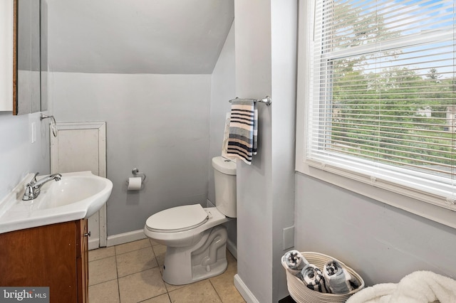 half bath with toilet, tile patterned floors, vanity, and baseboards