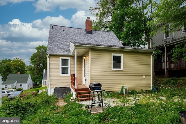 rear view of property with a chimney and a shingled roof