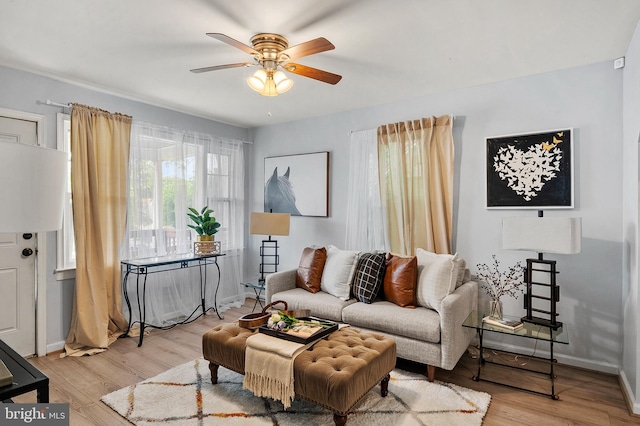 living room featuring ceiling fan, light wood-type flooring, and baseboards