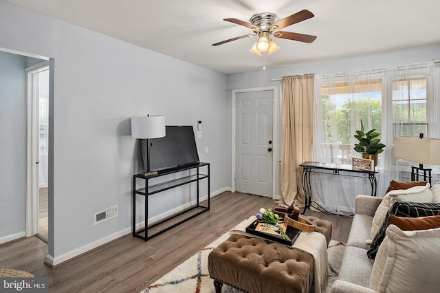 living room with ceiling fan, baseboards, and wood finished floors