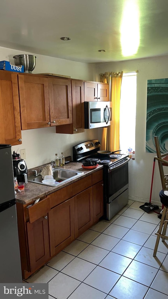 kitchen with light tile patterned flooring, stainless steel appliances, and sink