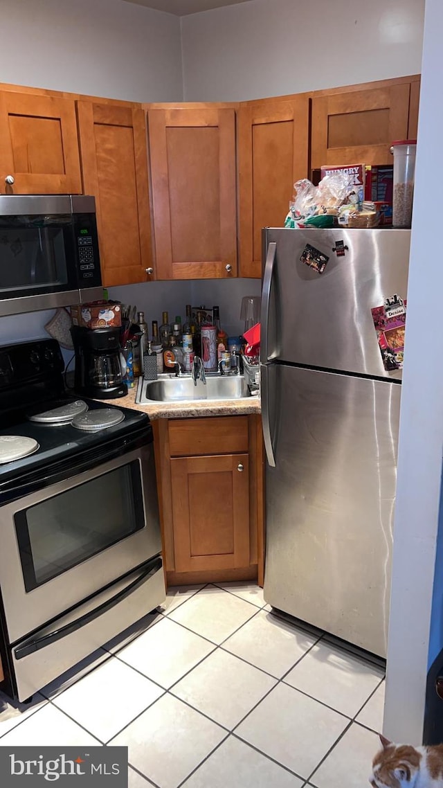 kitchen with stainless steel appliances, sink, and light tile patterned floors