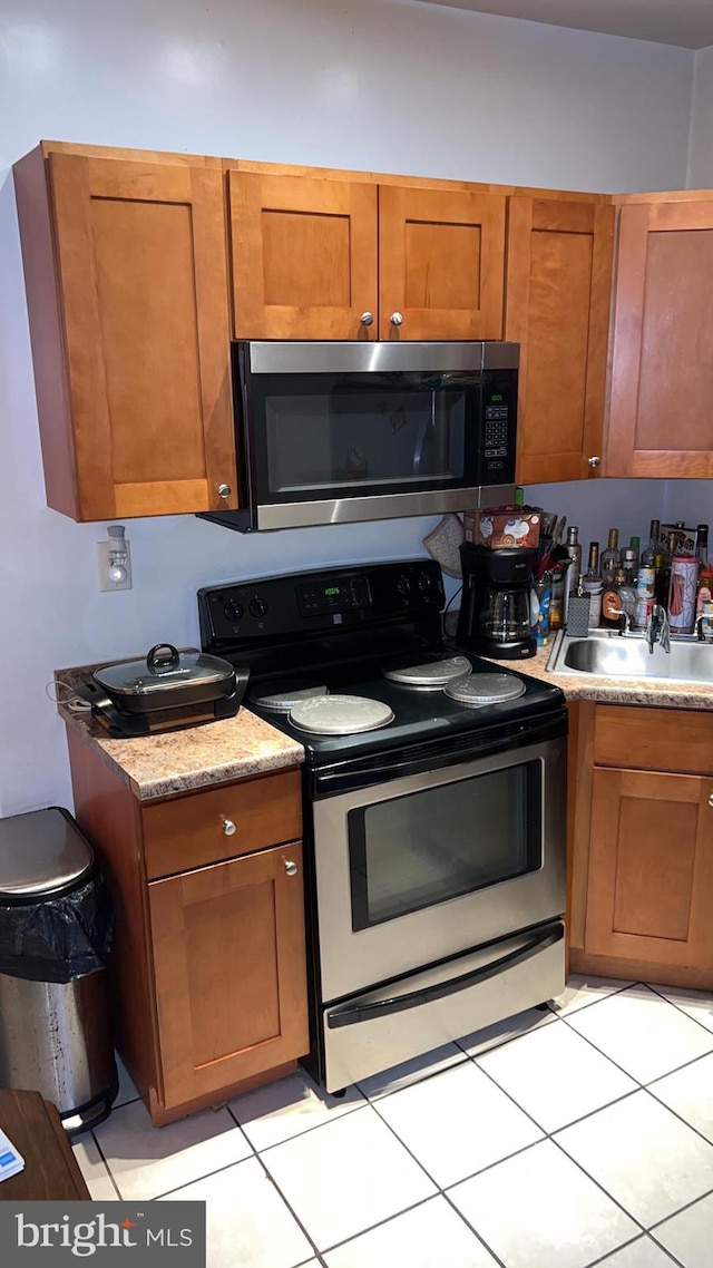 kitchen with appliances with stainless steel finishes, sink, and light tile patterned floors