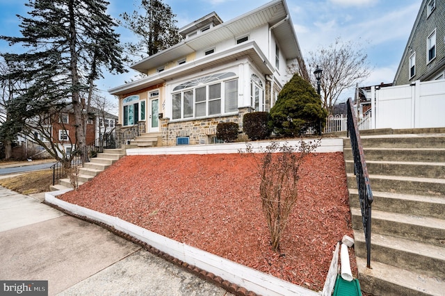 view of front facade with stone siding and fence