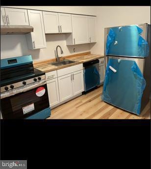 kitchen featuring light wood-type flooring, appliances with stainless steel finishes, sink, and white cabinets