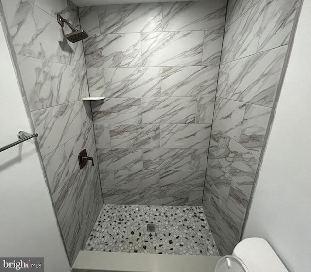 bathroom featuring toilet and a tile shower