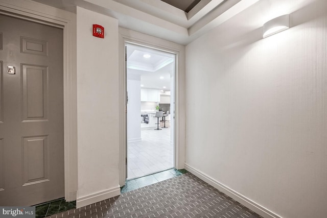 hallway featuring ornamental molding and a raised ceiling