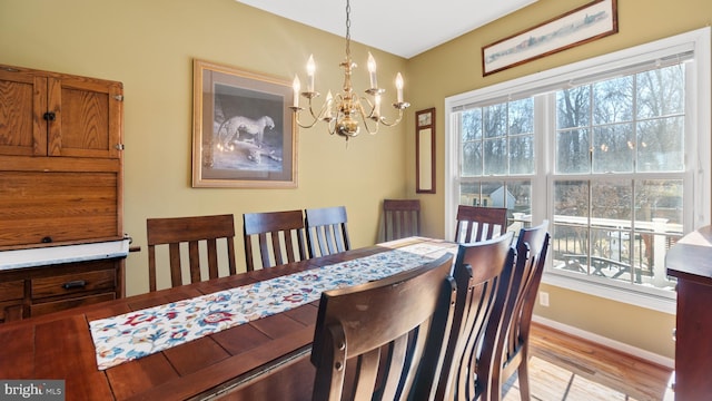 dining space featuring a chandelier, baseboards, light wood-style flooring, and a healthy amount of sunlight