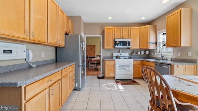 kitchen featuring light tile patterned floors, appliances with stainless steel finishes, a sink, and recessed lighting