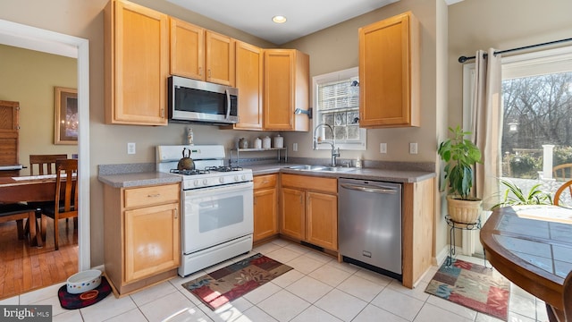 kitchen with light tile patterned floors, appliances with stainless steel finishes, light brown cabinetry, a sink, and recessed lighting