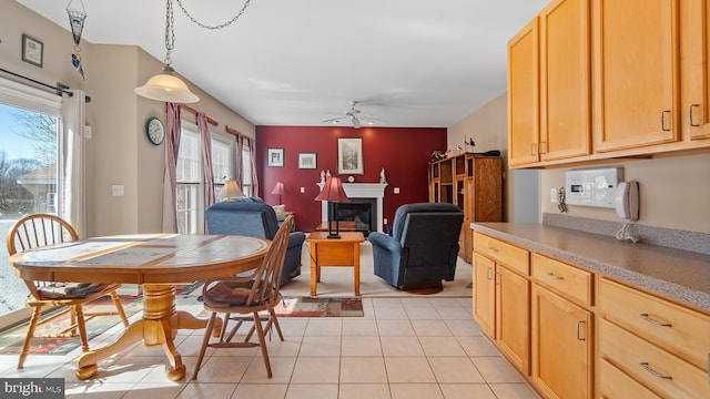 dining area featuring light tile patterned floors, a ceiling fan, and a glass covered fireplace