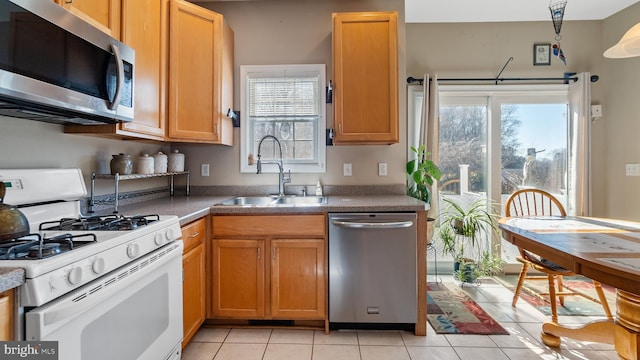 kitchen featuring stainless steel appliances, plenty of natural light, a sink, and light tile patterned floors