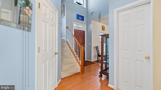 entryway featuring a high ceiling, stairway, light wood-type flooring, and baseboards