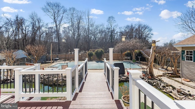 dock area featuring a water view, fence, and a fenced in pool