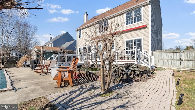 rear view of house featuring a fenced backyard, a patio, a chimney, and a wooden deck