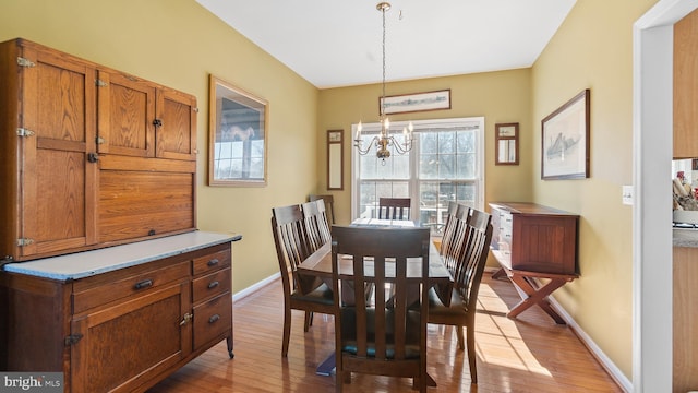 dining room featuring a chandelier, light wood-style flooring, and baseboards