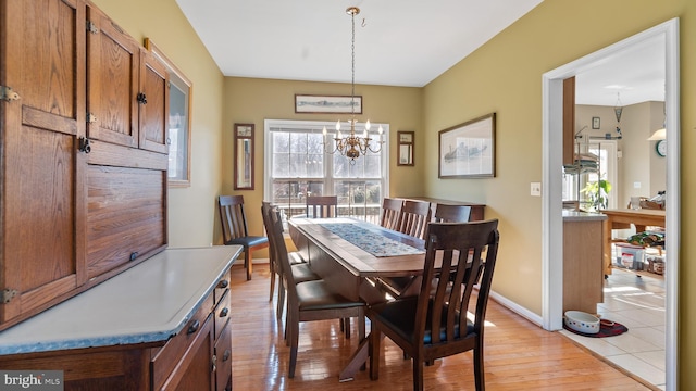 dining room with baseboards, an inviting chandelier, and light wood-style floors