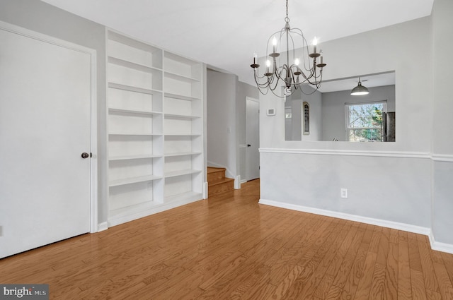 interior space with stairway, baseboards, an inviting chandelier, and wood finished floors