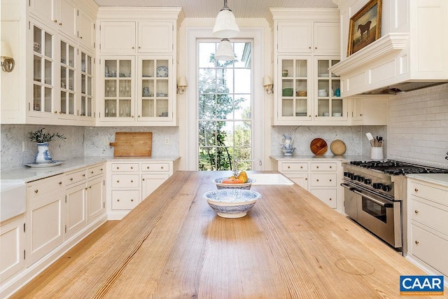 kitchen with white cabinetry, tasteful backsplash, double oven range, custom range hood, and pendant lighting