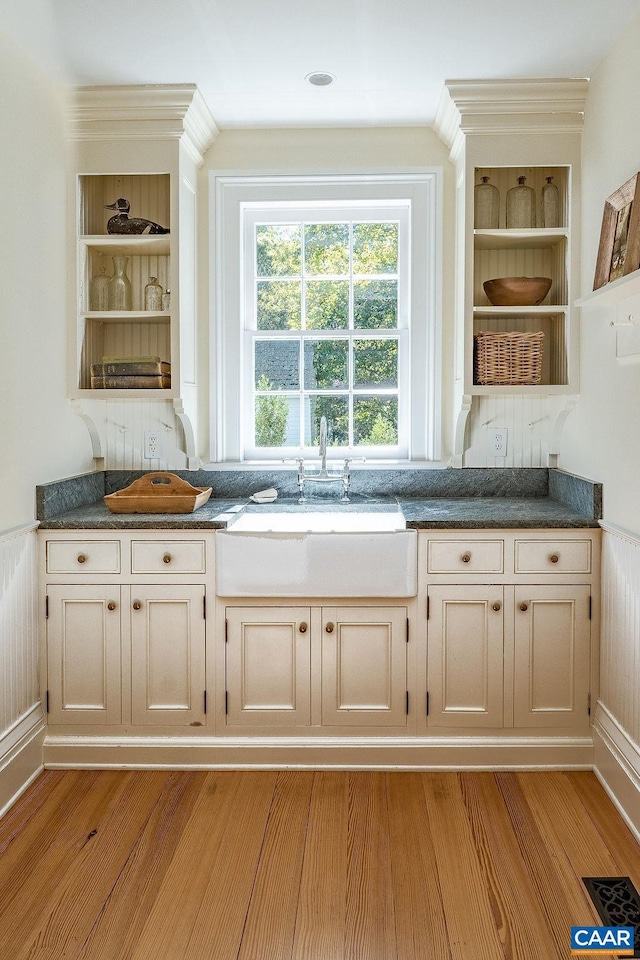 bar featuring sink, built in shelves, and light hardwood / wood-style flooring