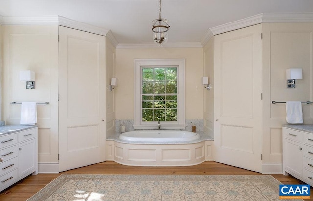 bathroom with vanity, hardwood / wood-style flooring, ornamental molding, and a bathing tub