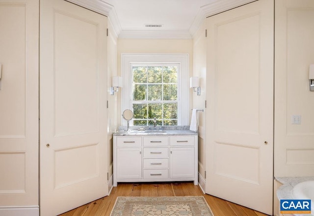 interior space with sink, wood-type flooring, and ornamental molding