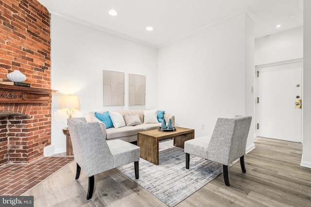 living room featuring a brick fireplace, crown molding, and light wood-type flooring