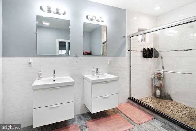 bathroom featuring a shower with door, vanity, hardwood / wood-style floors, and tile walls