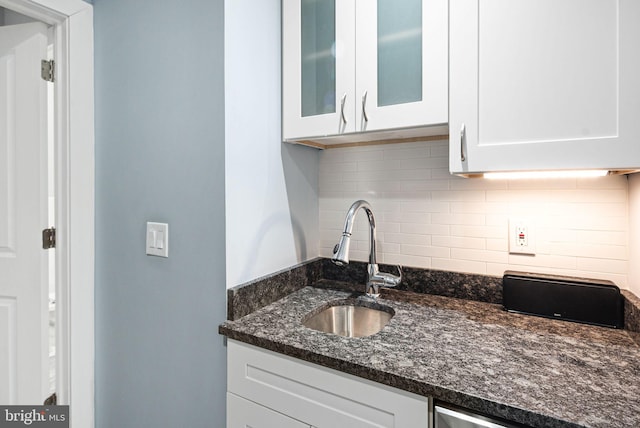 kitchen with white cabinetry, sink, backsplash, and dark stone counters