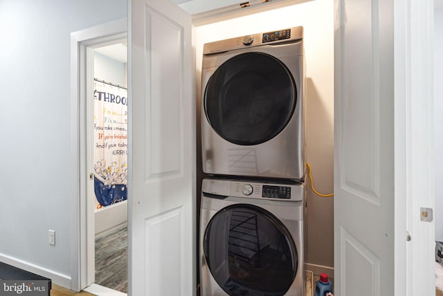 washroom featuring hardwood / wood-style flooring and stacked washing maching and dryer