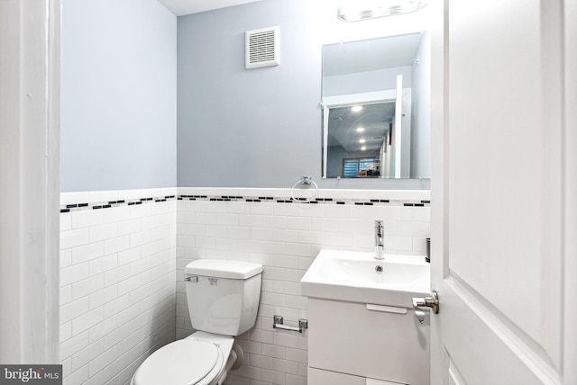 bathroom with vanity, tile walls, and toilet