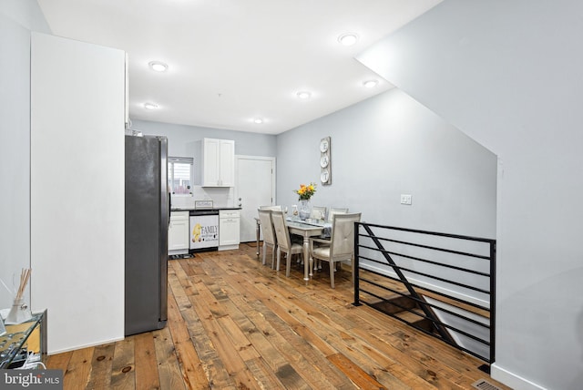 kitchen with appliances with stainless steel finishes, white cabinets, and light hardwood / wood-style floors