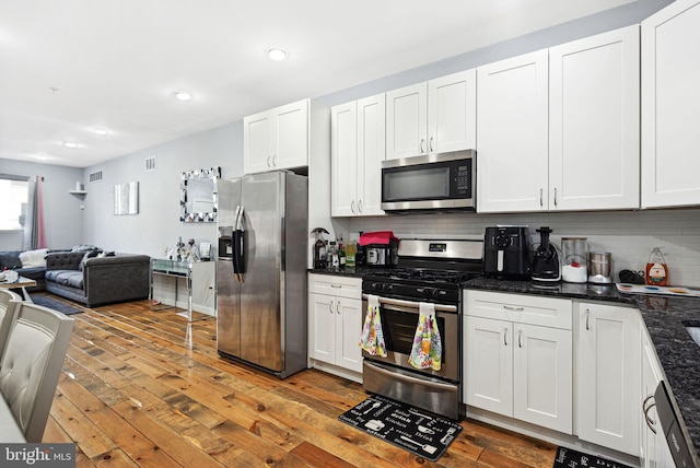 kitchen featuring decorative backsplash, stainless steel appliances, white cabinets, and light wood-type flooring