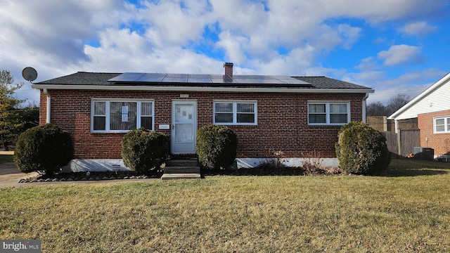 view of front facade with a front yard, central AC unit, and solar panels