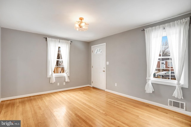 foyer with an inviting chandelier and light hardwood / wood-style flooring