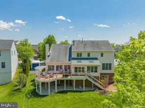 rear view of property featuring a lawn, a wooden deck, and stairs