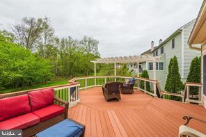 wooden deck with a pergola and an outdoor hangout area