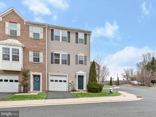 view of property featuring brick siding, driveway, an attached garage, and fence