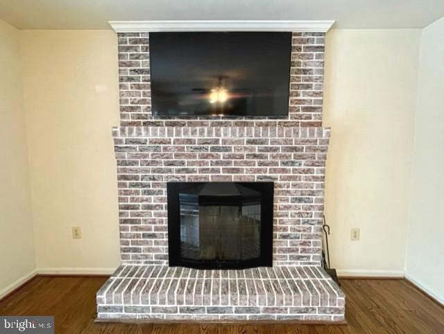 details featuring a brick fireplace, wood finished floors, and baseboards