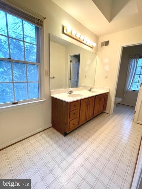 bathroom with double vanity, visible vents, toilet, tile patterned floors, and a sink